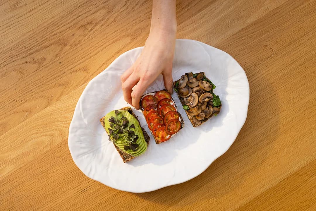Seeded bread topped with avocado, tomatoes and mushrooms on a sunlit table at Aro Hā.